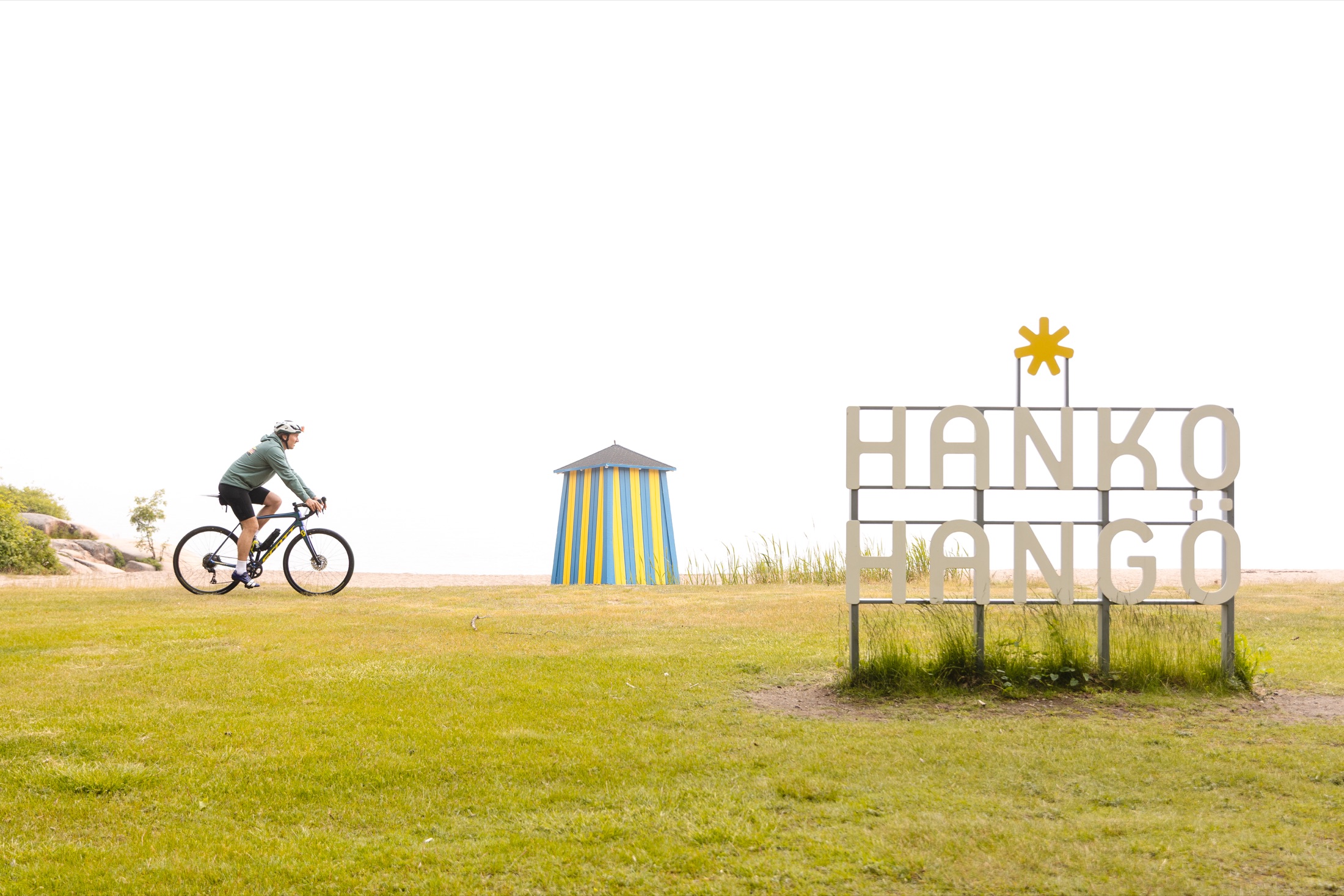 Pyöräilijä Hangon rannalla Hanko-kyltin luona